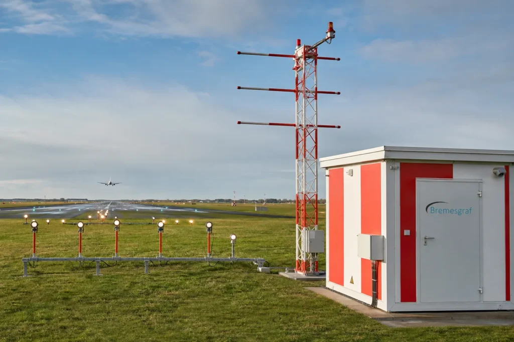 Instrument landing system and approach lighting beside a runway, with an aircraft on approach